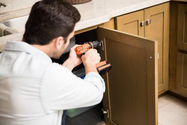 man using power drill on kitchen cabinet refinishing